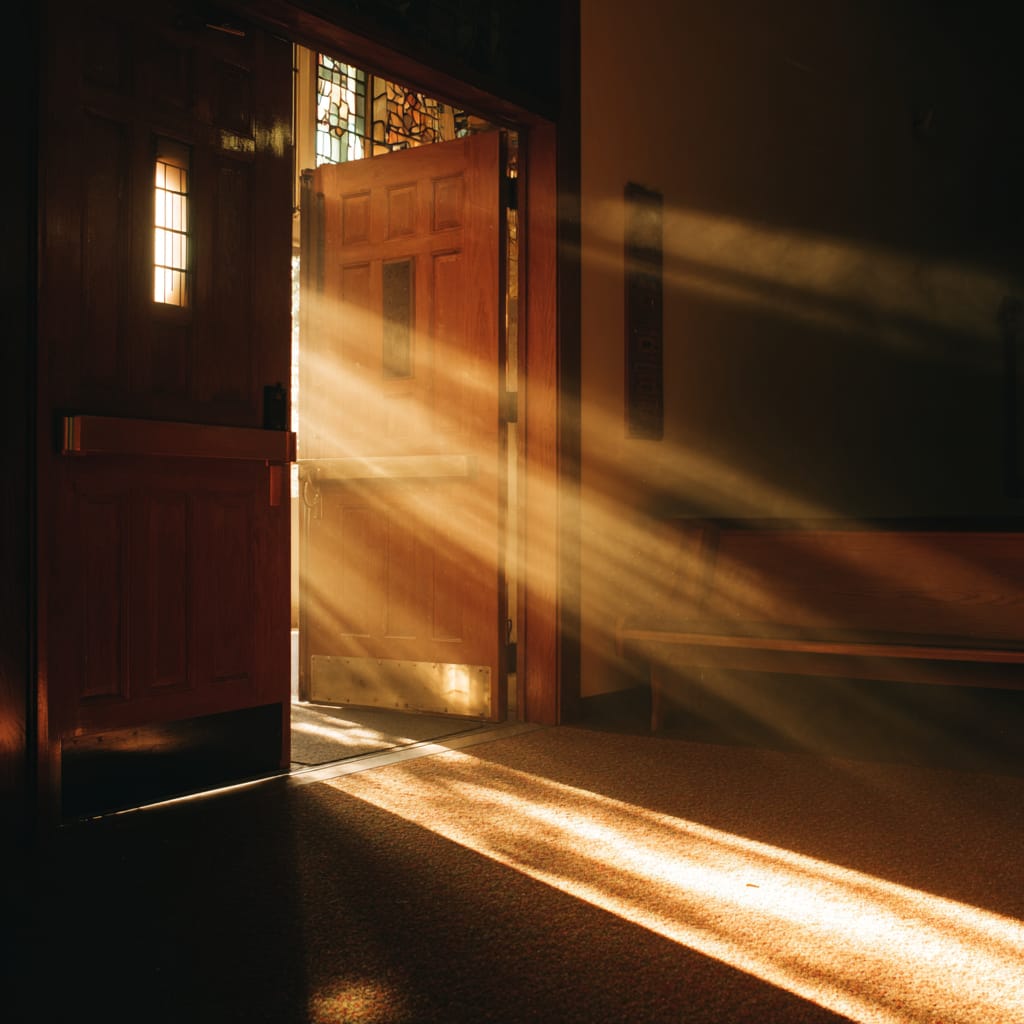 Sunlight streaming through an open wooden door, illuminating a carpeted floor.
