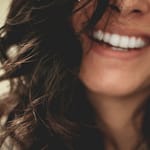 Close-up of a smiling person with wavy dark hair.