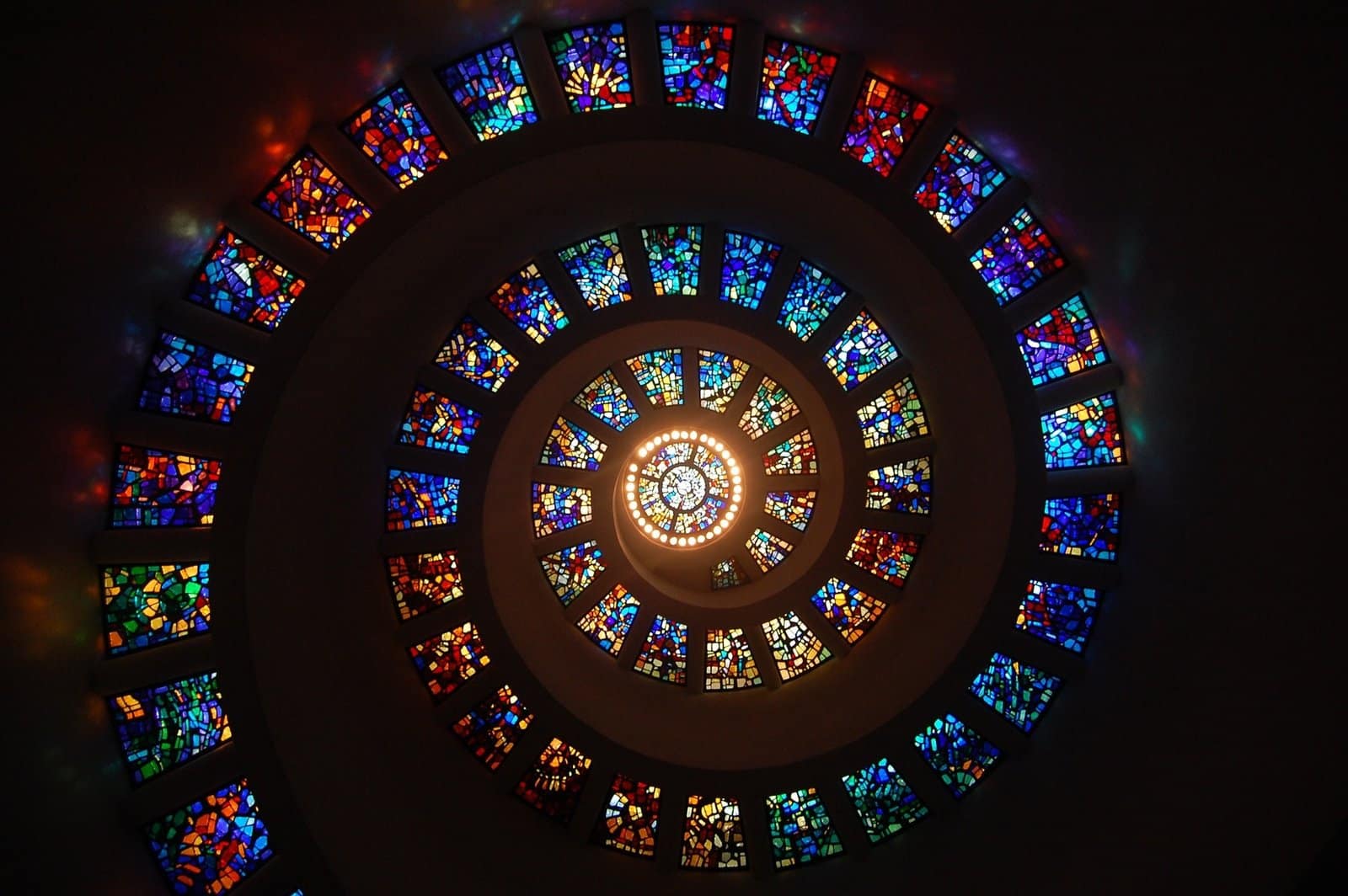 Spiral stained glass structure with vibrant colors viewed from below.
