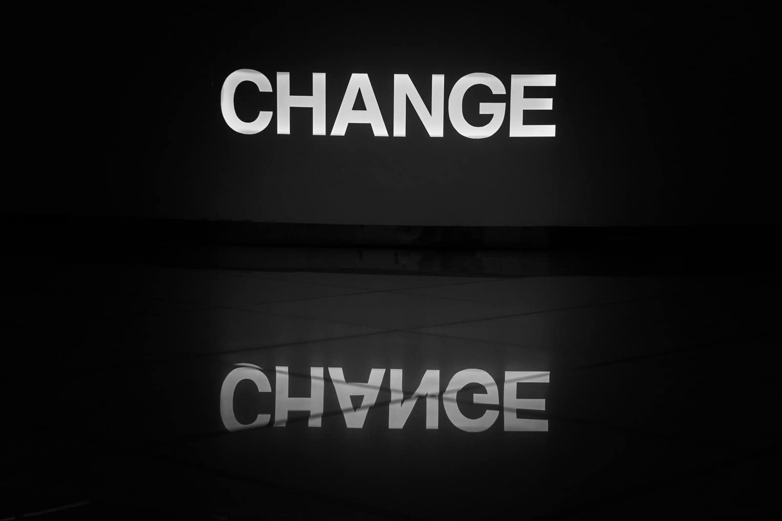 The word "CHANGE" in white capital letters on a black background, with its reflection below.