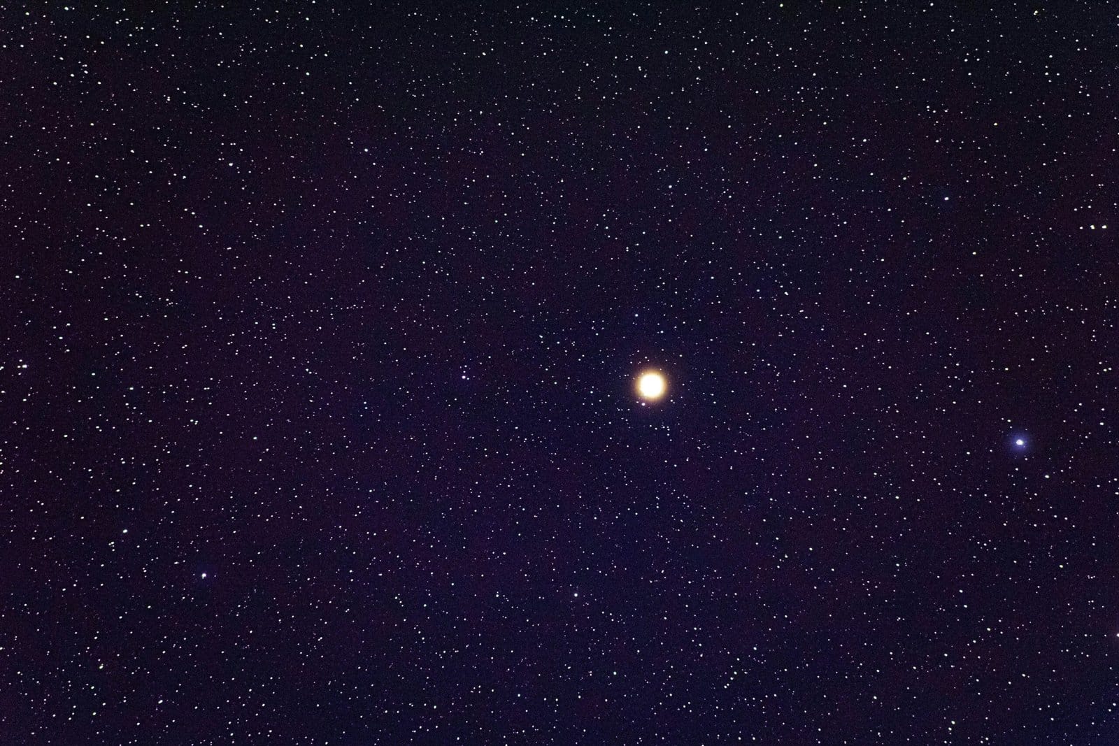 A starry night sky with a bright, prominent star in the center.