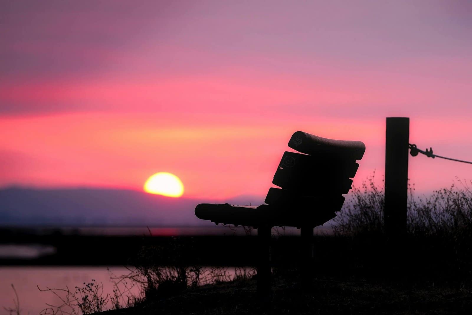 Scenic bench on hill with view of water, ideal for relaxation.
